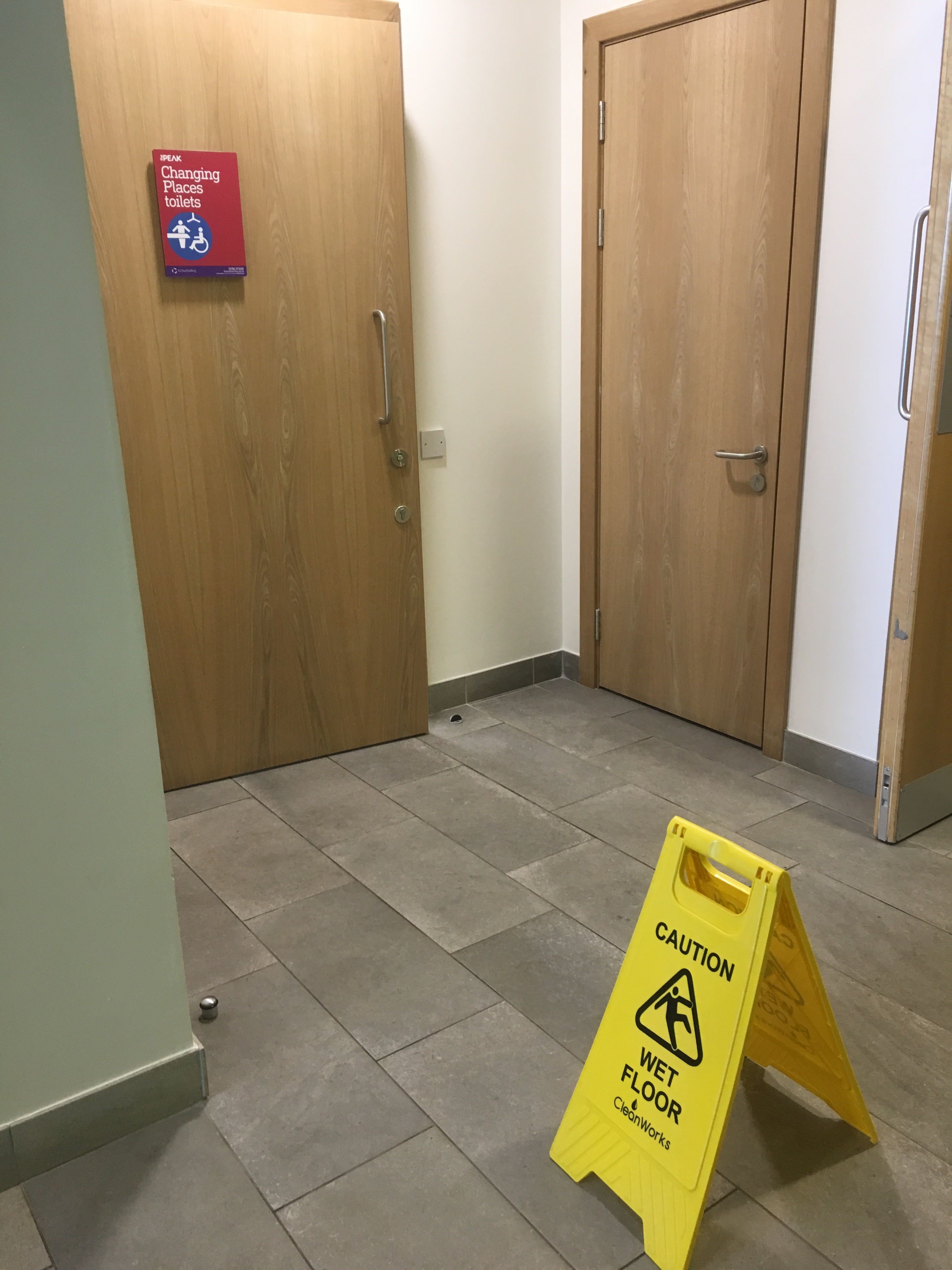 Photo of a sign saying 'Caution Wet Floor' outside a Changing Place Toilet