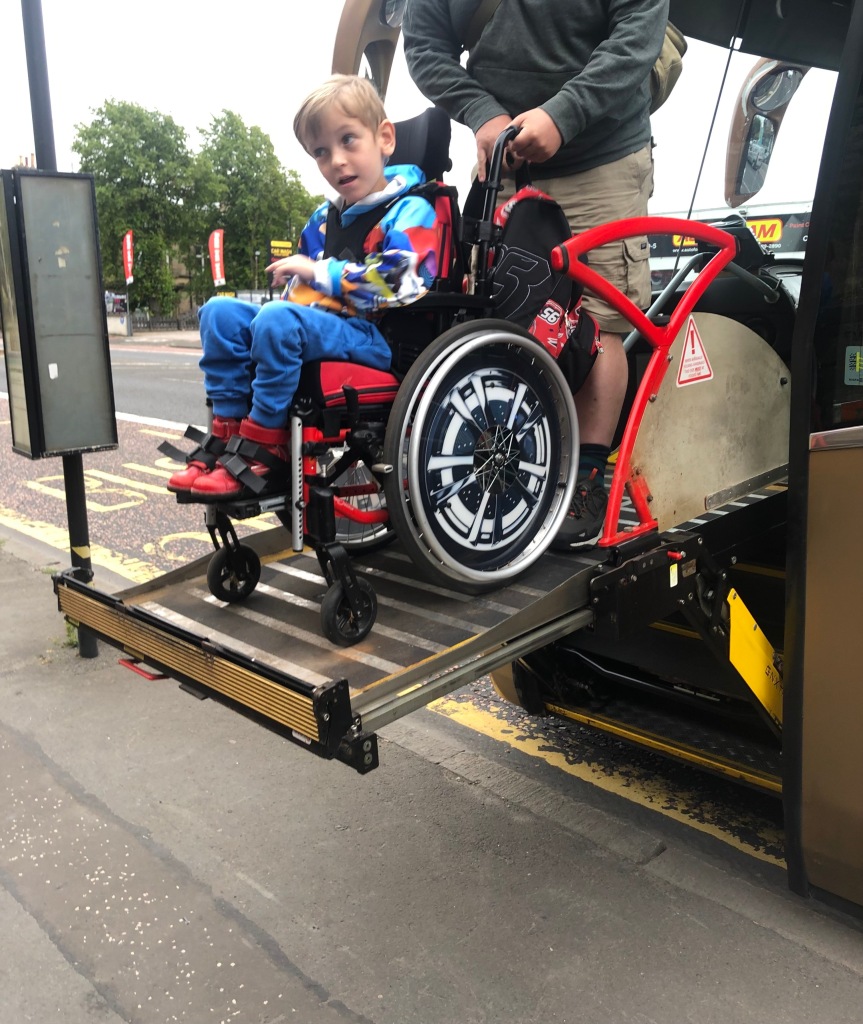 Quinns being lowered to the ground in his wheelchair on a lift attached to a coach.